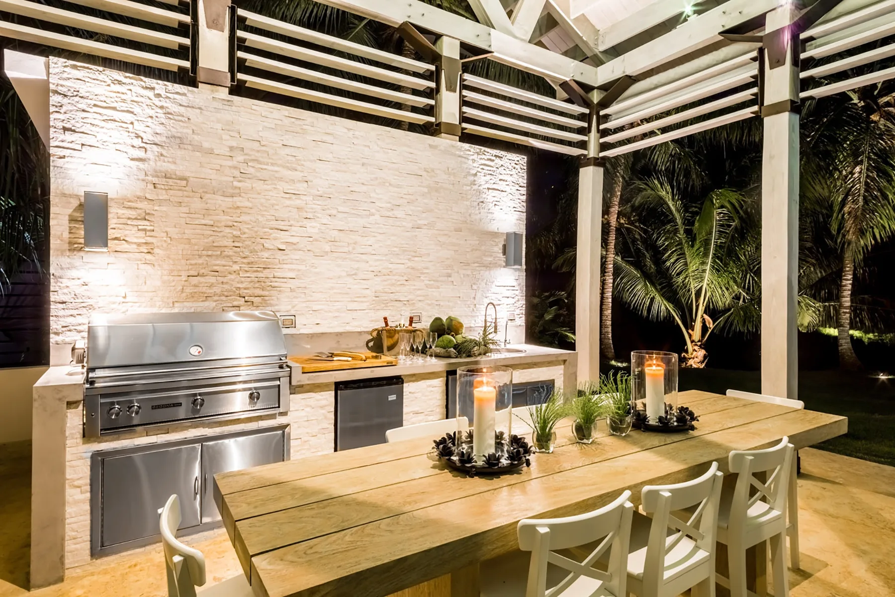 Una zona de comedor al aire libre con una mesa larga junto a una encimera de cocina.