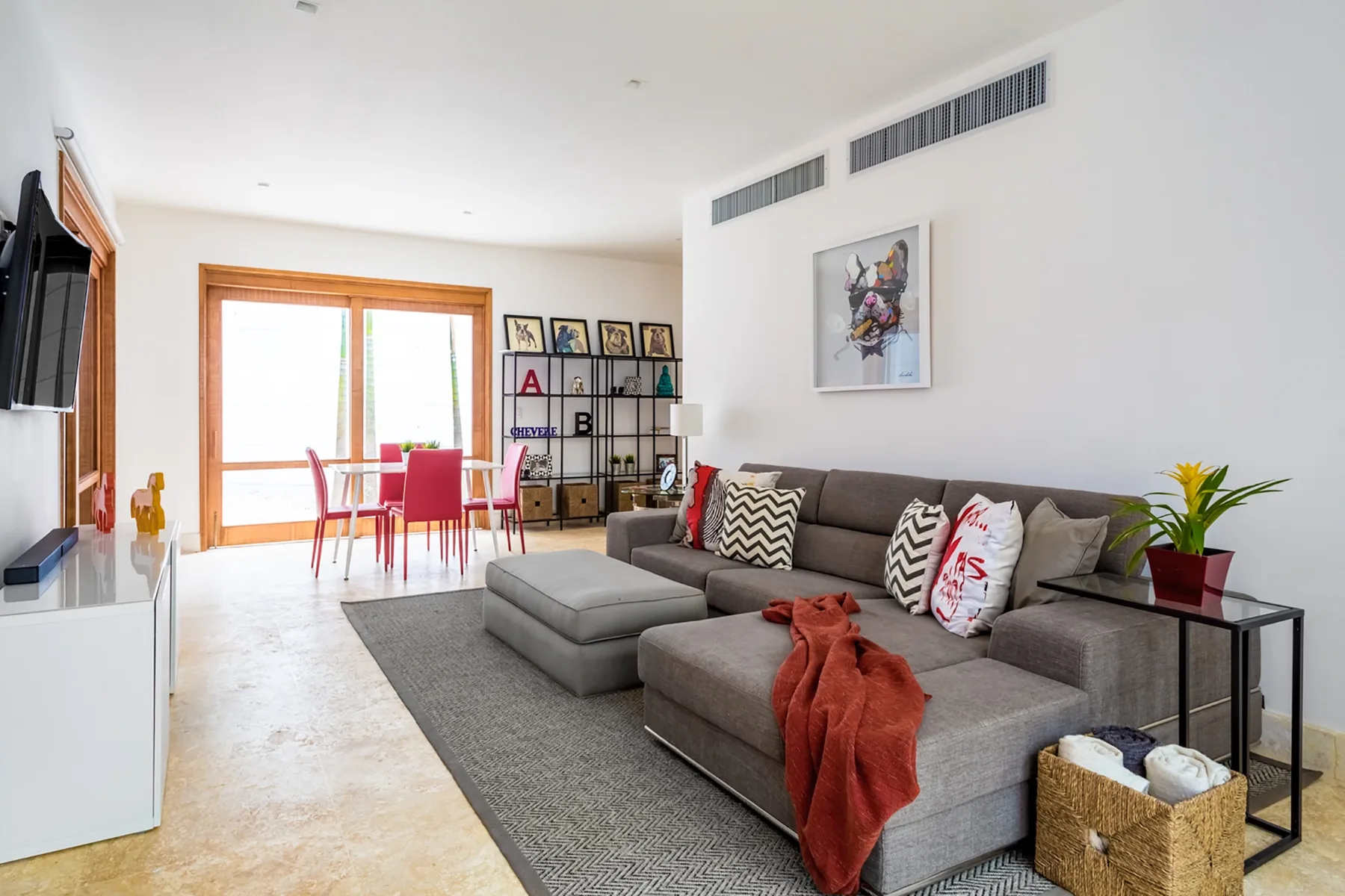 Una sala luminosa con asientos grises y una mesa de comedor junto a las ventanas.