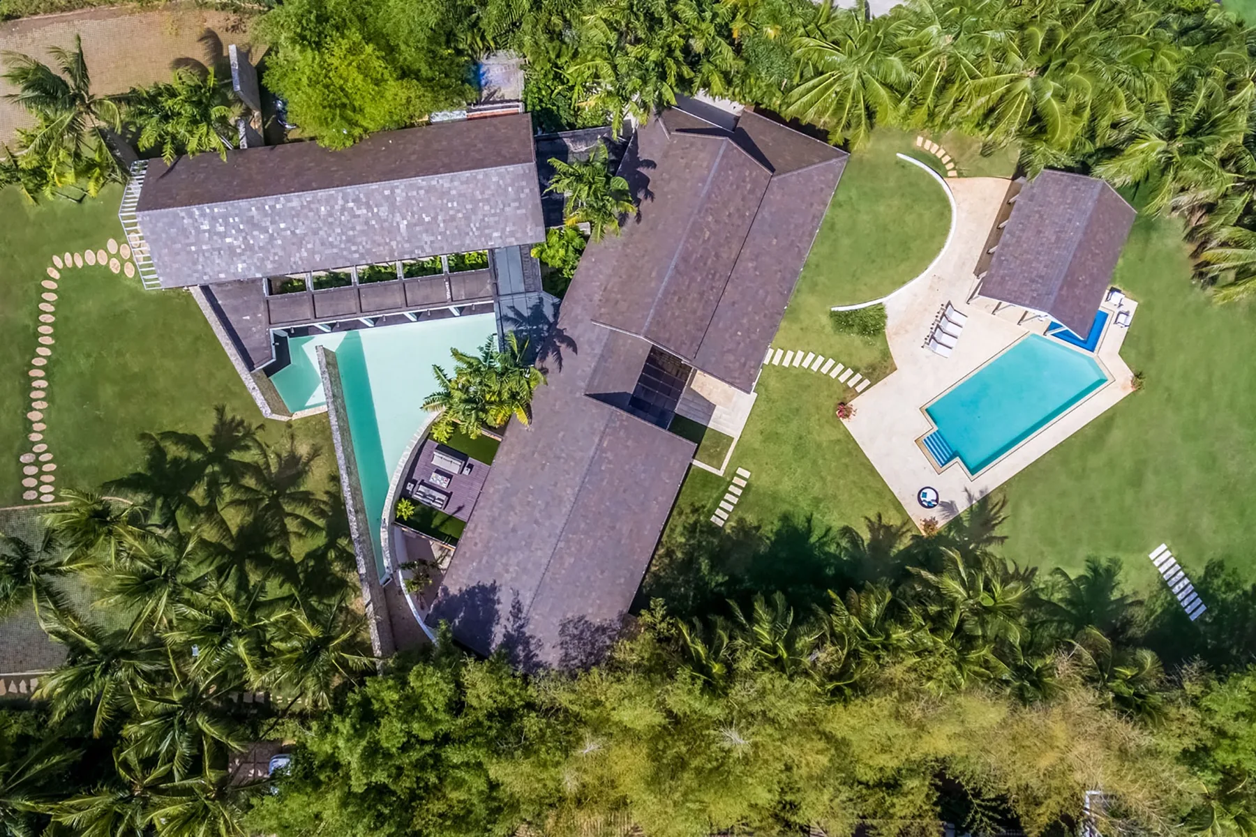 Vista aérea de una propiedad tropical con varios edificios y una piscina.