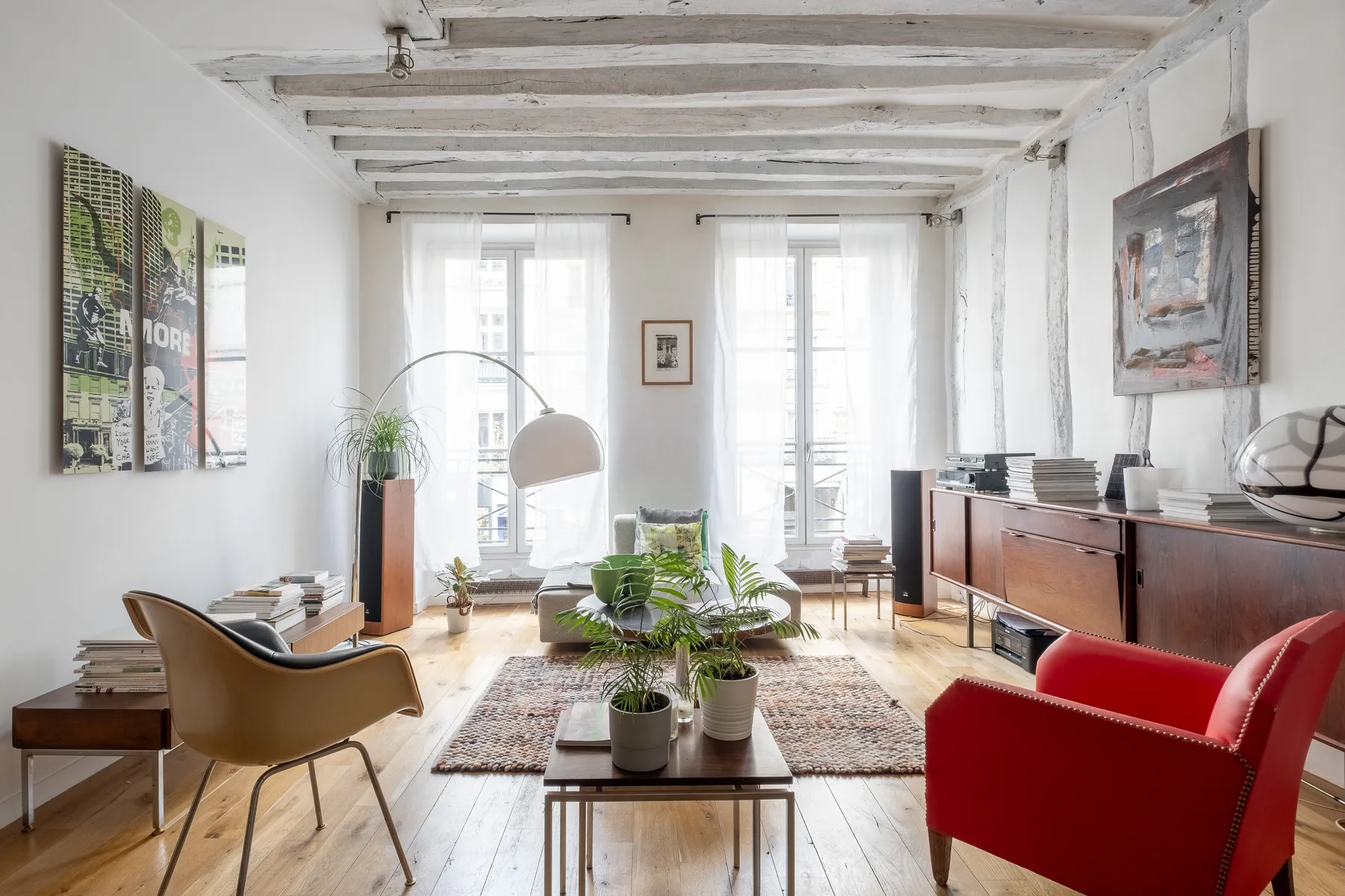 A bright living room with seating, a rug, and plants around a low table.