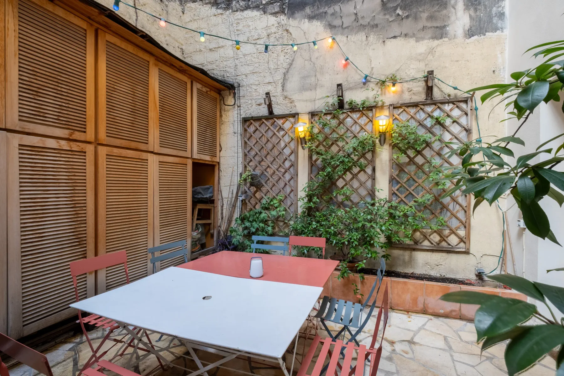 An outdoor patio with a dining table, seating, and climbing plants.