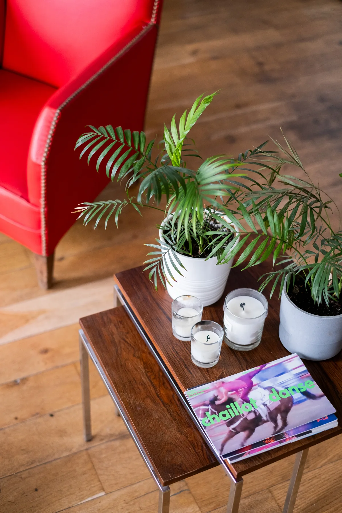 A seating area with a red armchair, potted plants, and a wooden coffee table.