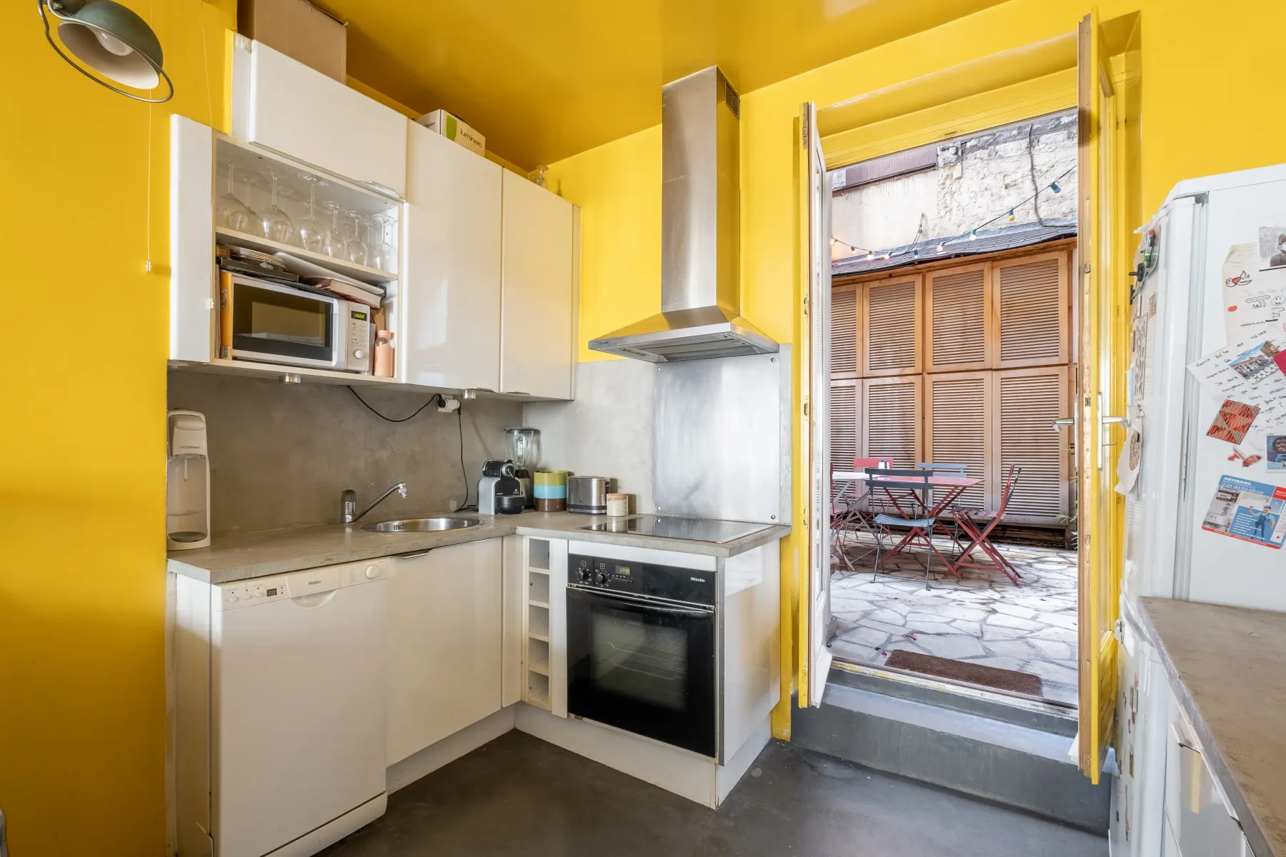 A compact kitchen with white cabinets opens onto a small patio.