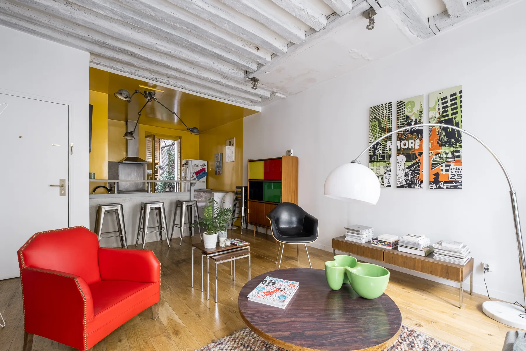 A bright living room with colorful seating and an open kitchen.