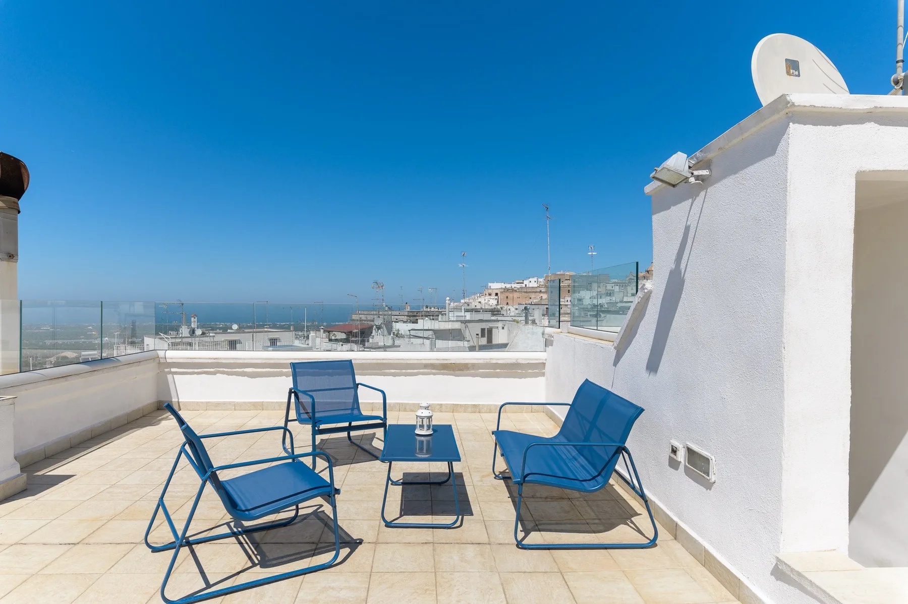 A rooftop terrace with blue seating and views of the surrounding city.