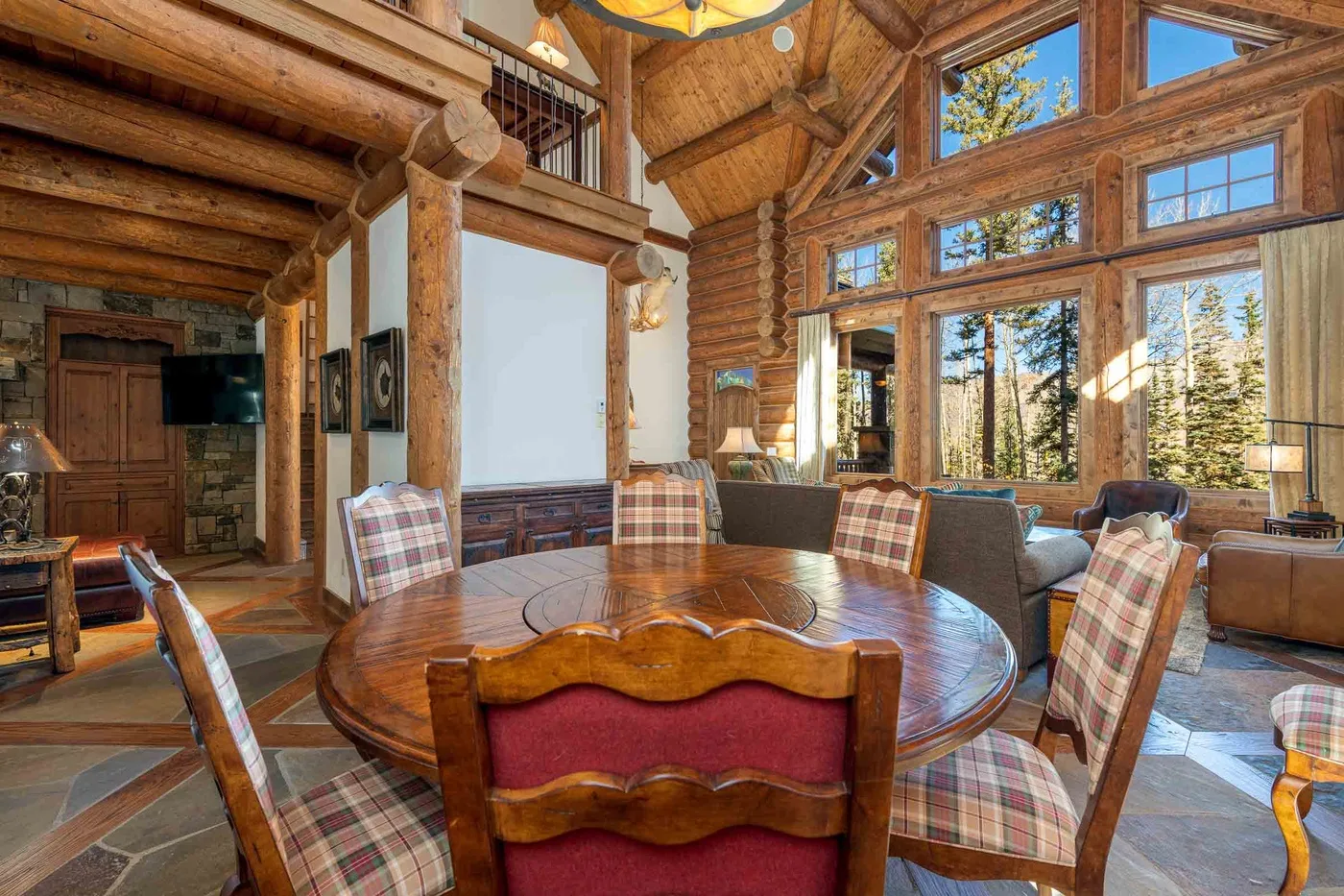 A timber-framed living and dining area with a round table and large windows.