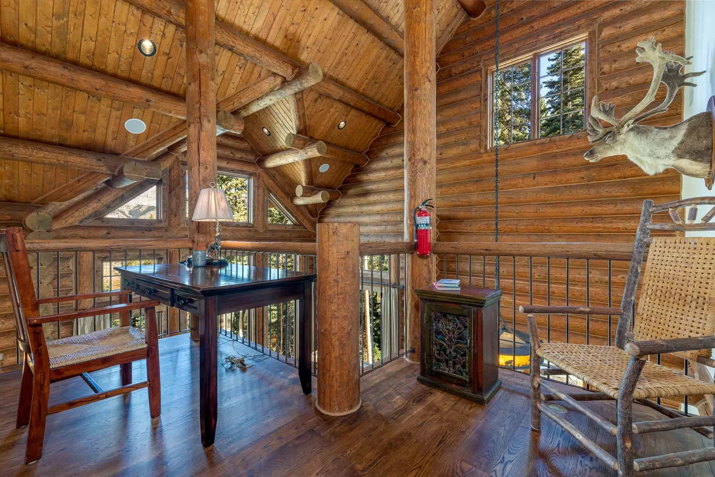 A rustic wood-paneled dining area with a table and chairs beneath a vaulted timber ceiling.