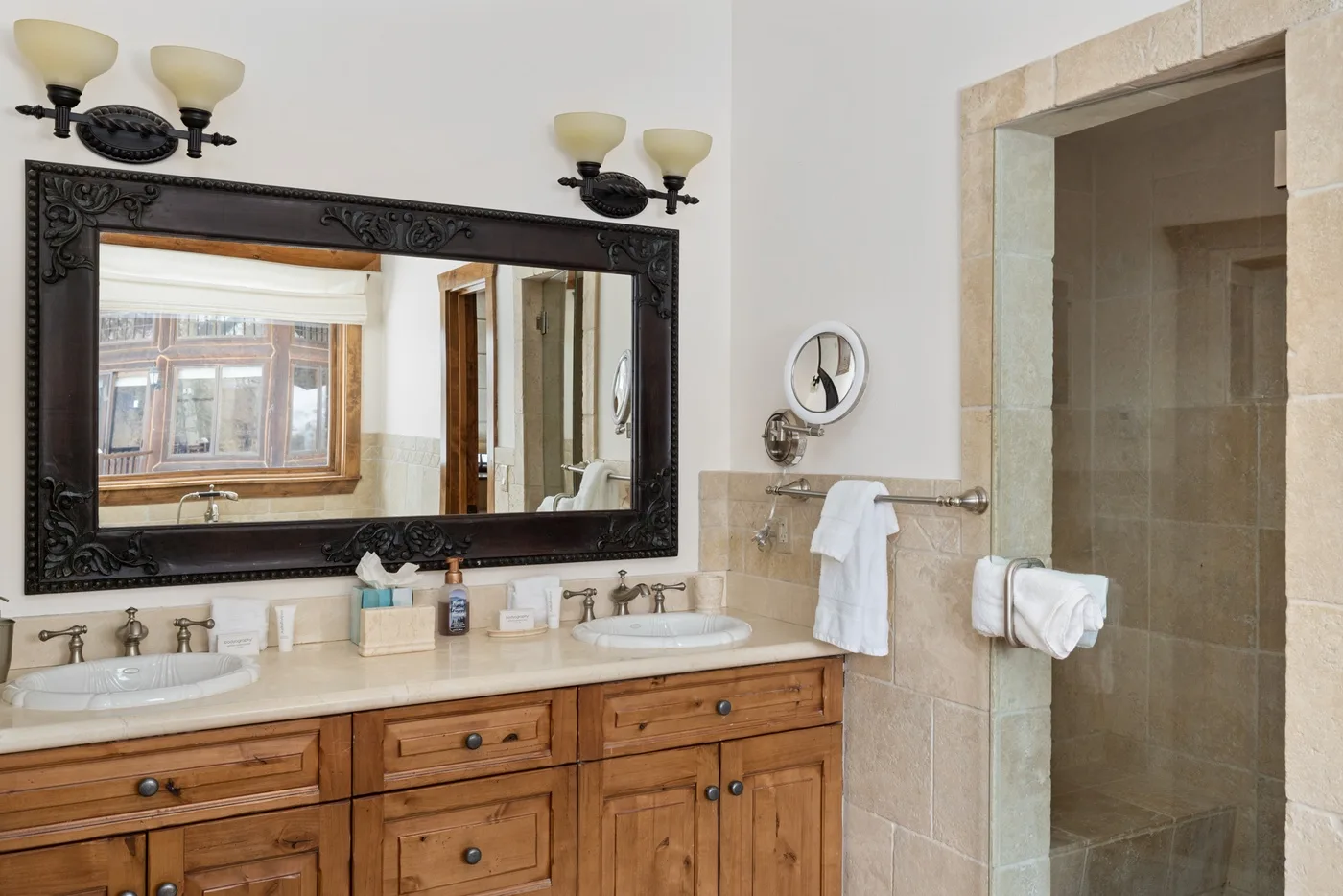 A bathroom vanity with a large mirror and an open shower area.