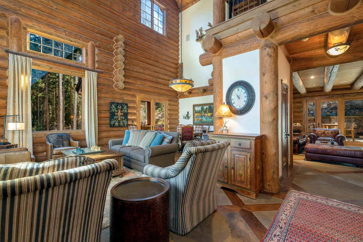 A wood-paneled living room with striped seating and a large wall clock.