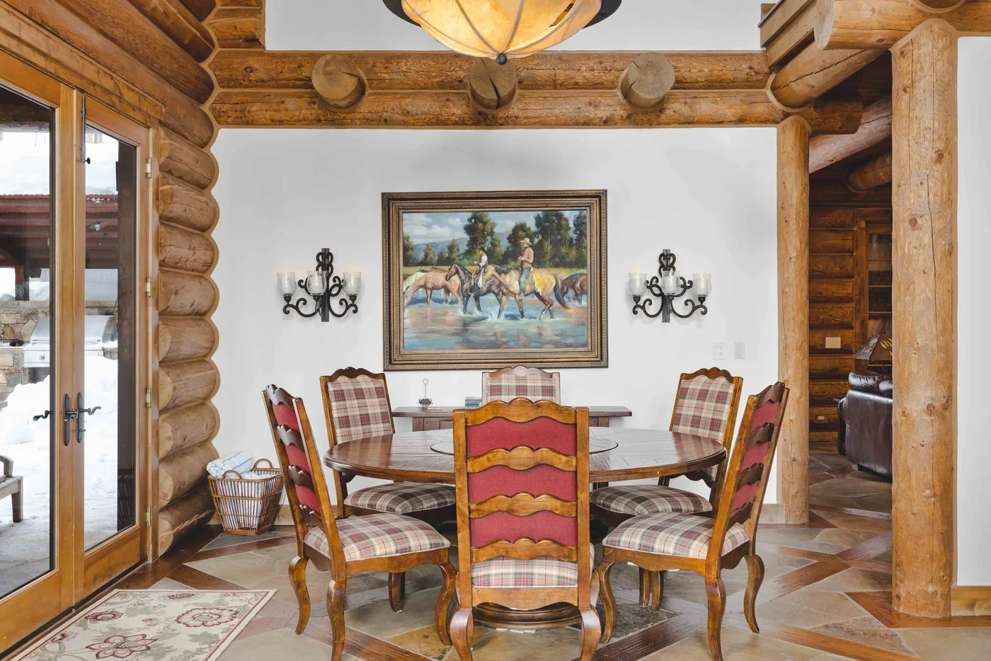 A dining area with a wooden table and chairs beneath a framed painting.