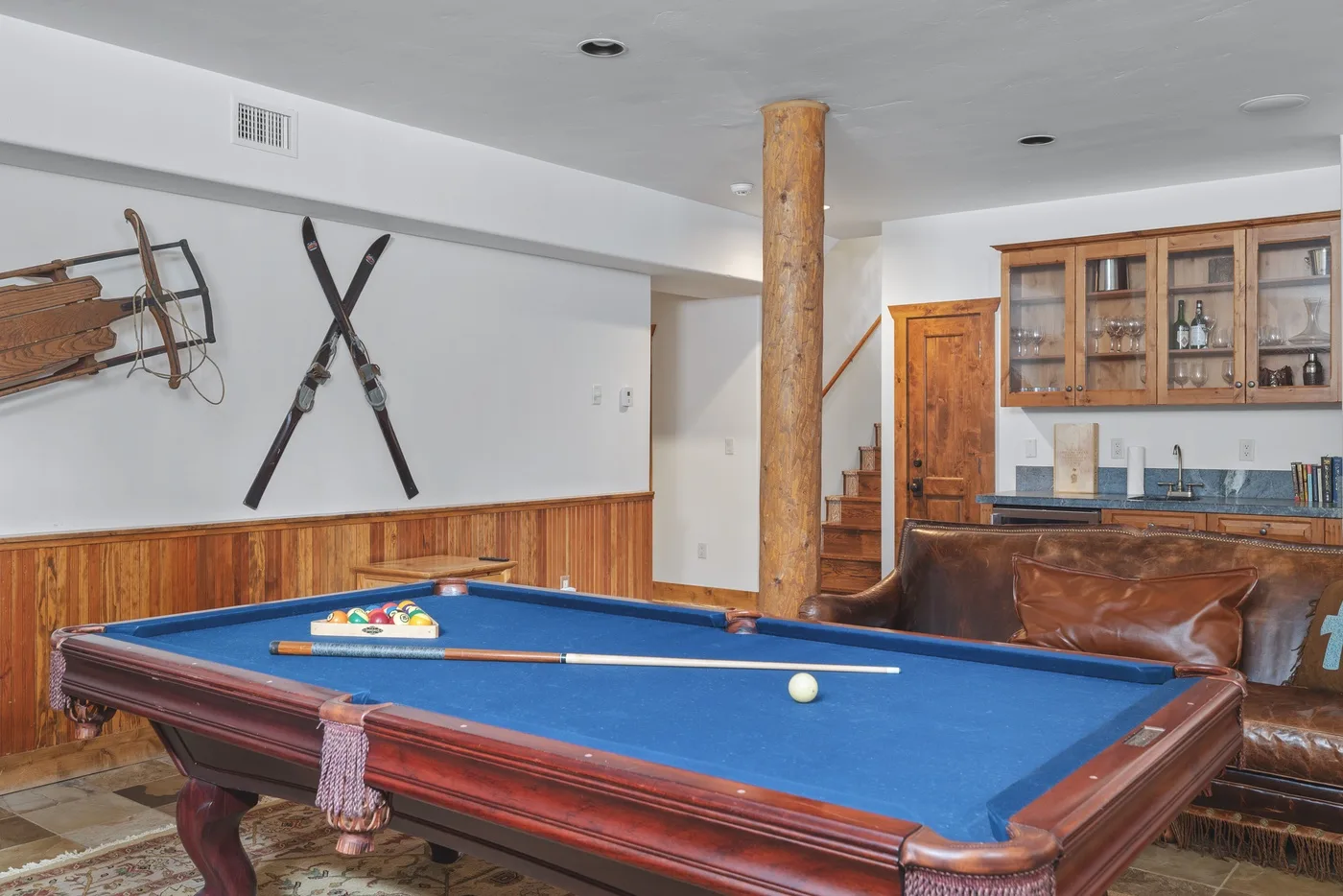 A game room features a blue-felt pool table and wood-paneled walls.