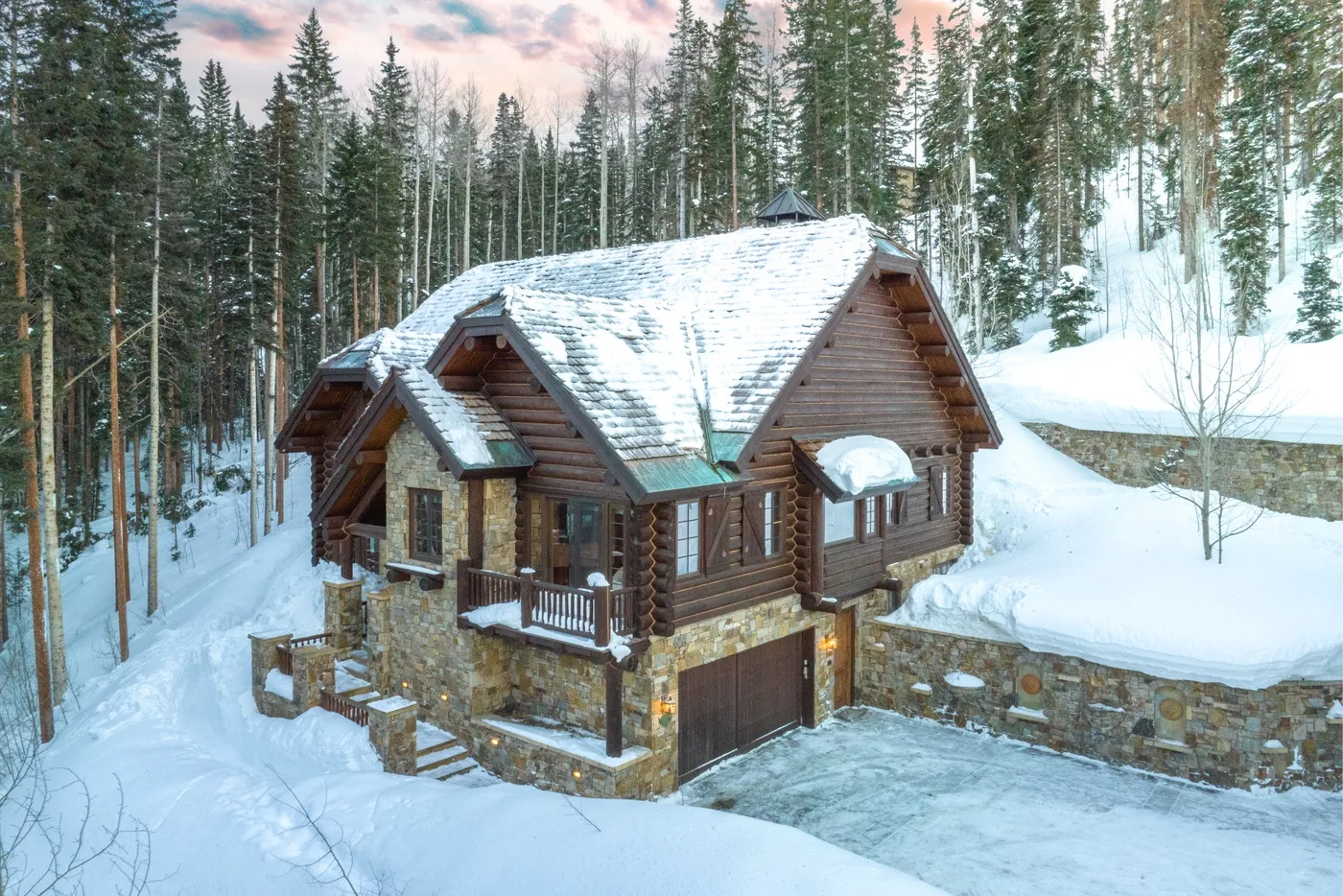A log cabin sits in a snowy forest, with evergreen trees surrounding it.