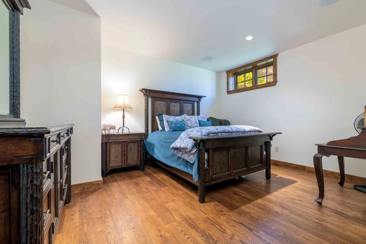 A bedroom with a wooden bed, blue bedding, and a bedside lamp.