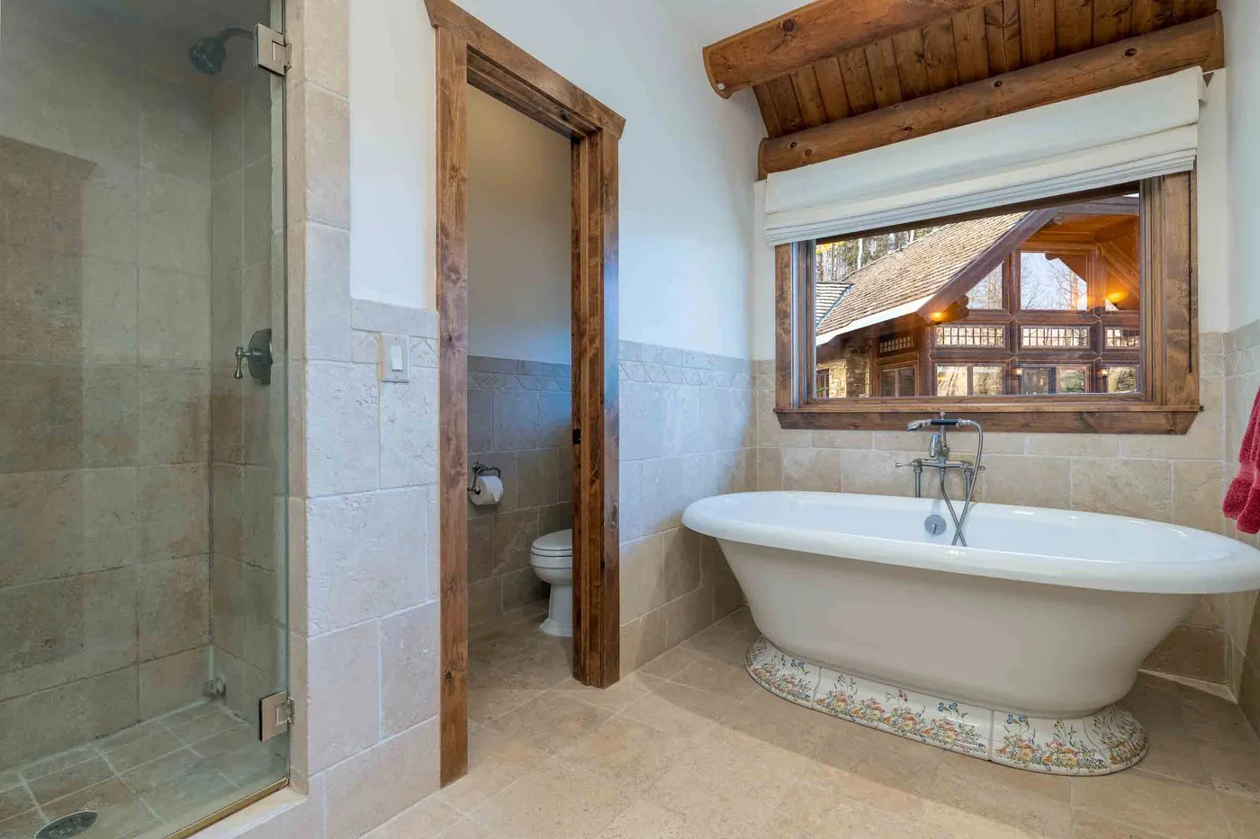 A bathroom with a freestanding bathtub beneath a window and a glass shower.