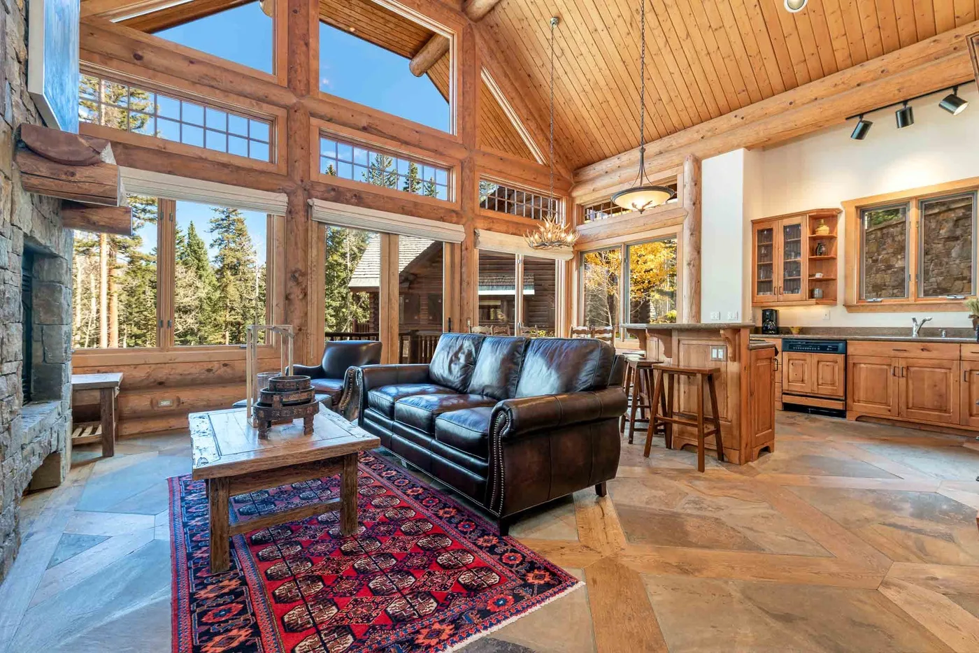 A spacious living room with large windows, seating, and a patterned rug.