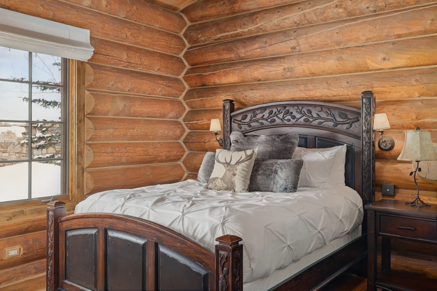 A bedroom with a large bed against warm wood-paneled walls.