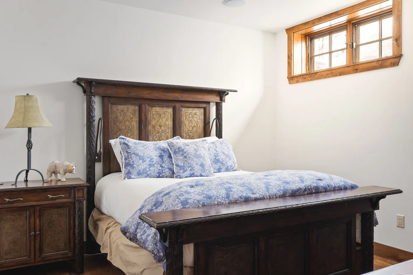 A bedroom with a wooden bed dressed in blue-and-white patterned bedding.