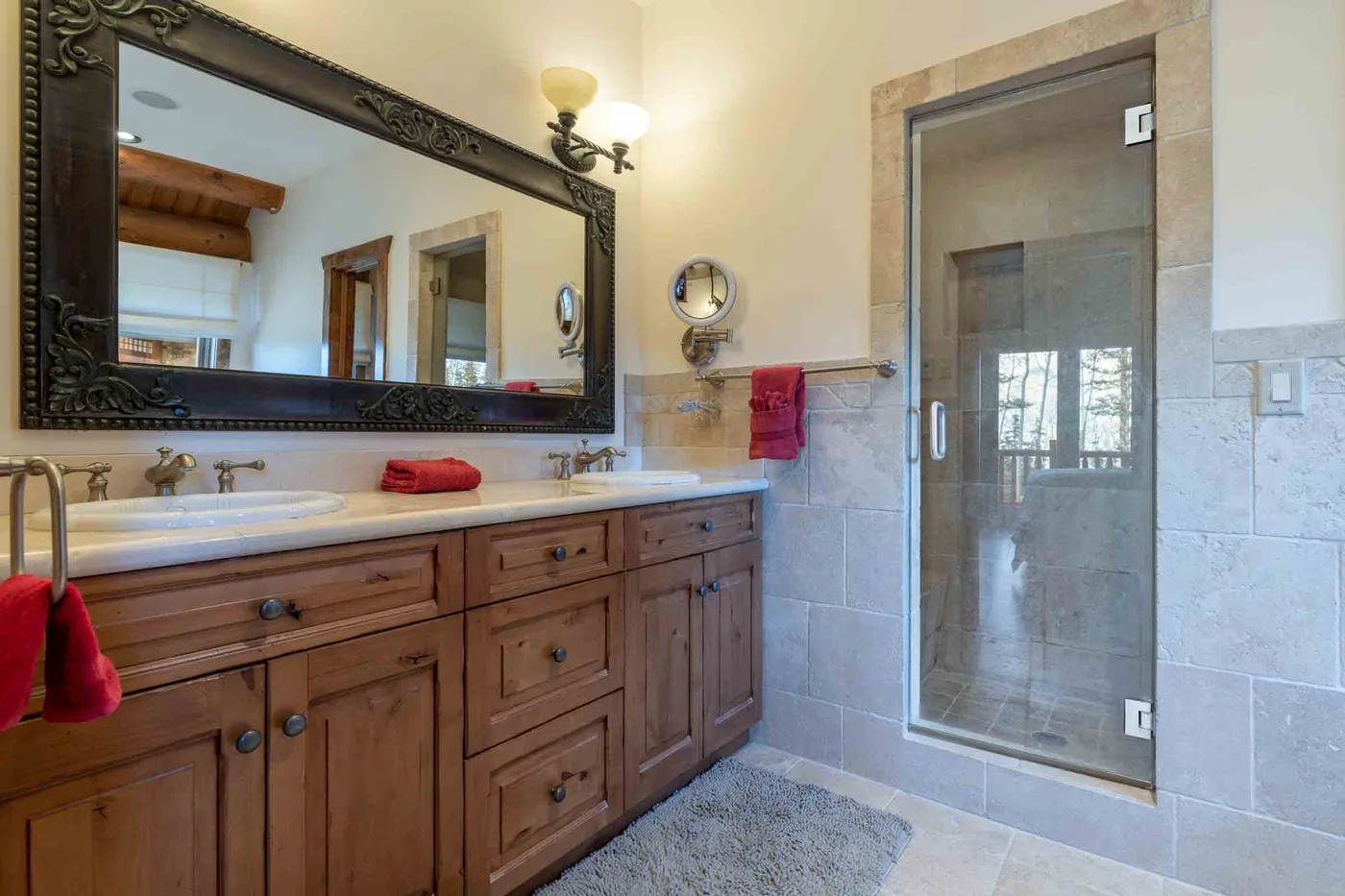 A bathroom with a long wooden vanity, large mirror, and glass shower.