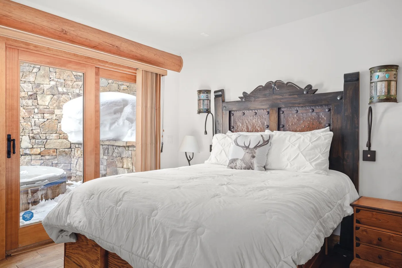 A bedroom with a large bed and a wooden-framed glass door.