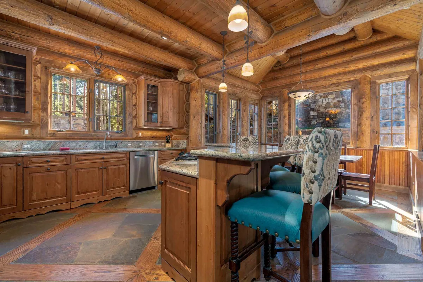 A rustic kitchen with wooden cabinets, a central island, and a dining table.