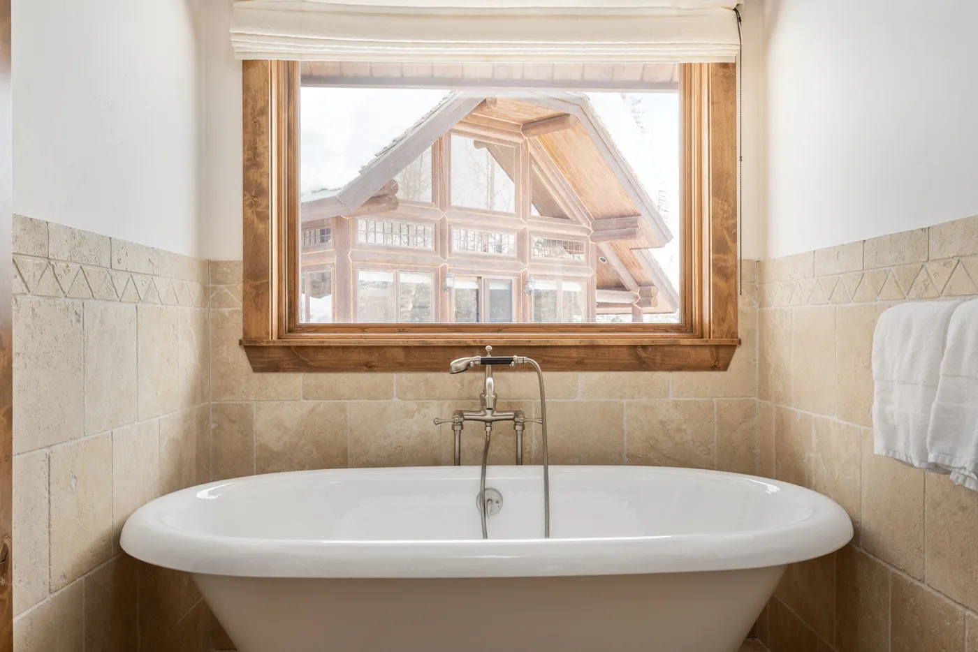A bathtub sits beneath a window overlooking a timber-framed building.