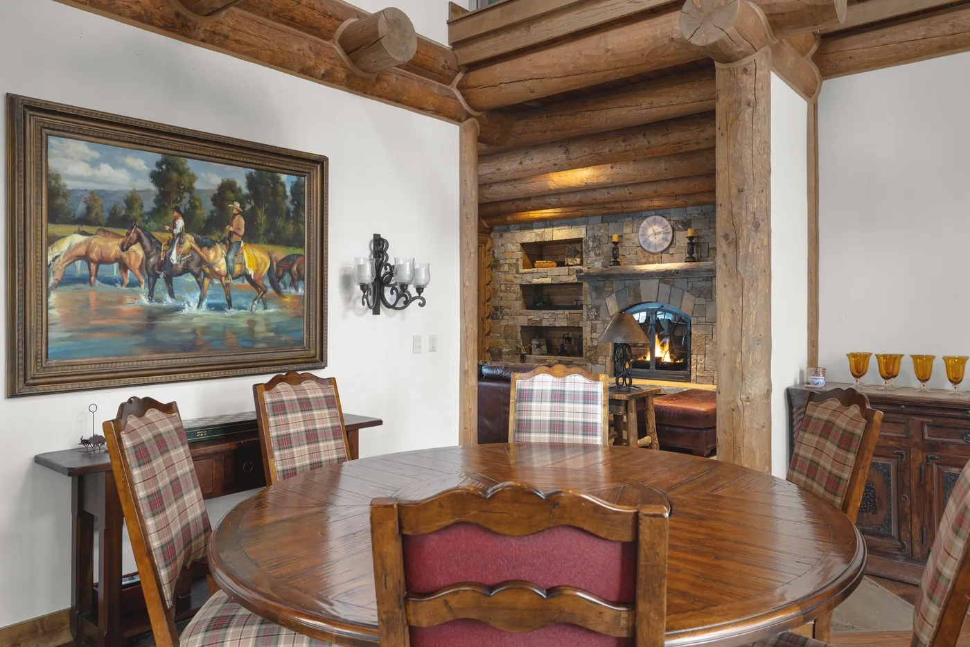 A dining area with a wooden table and chairs beside a stone fireplace.