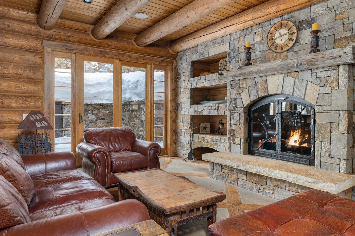 A rustic living room with leather seating and a stone fireplace.