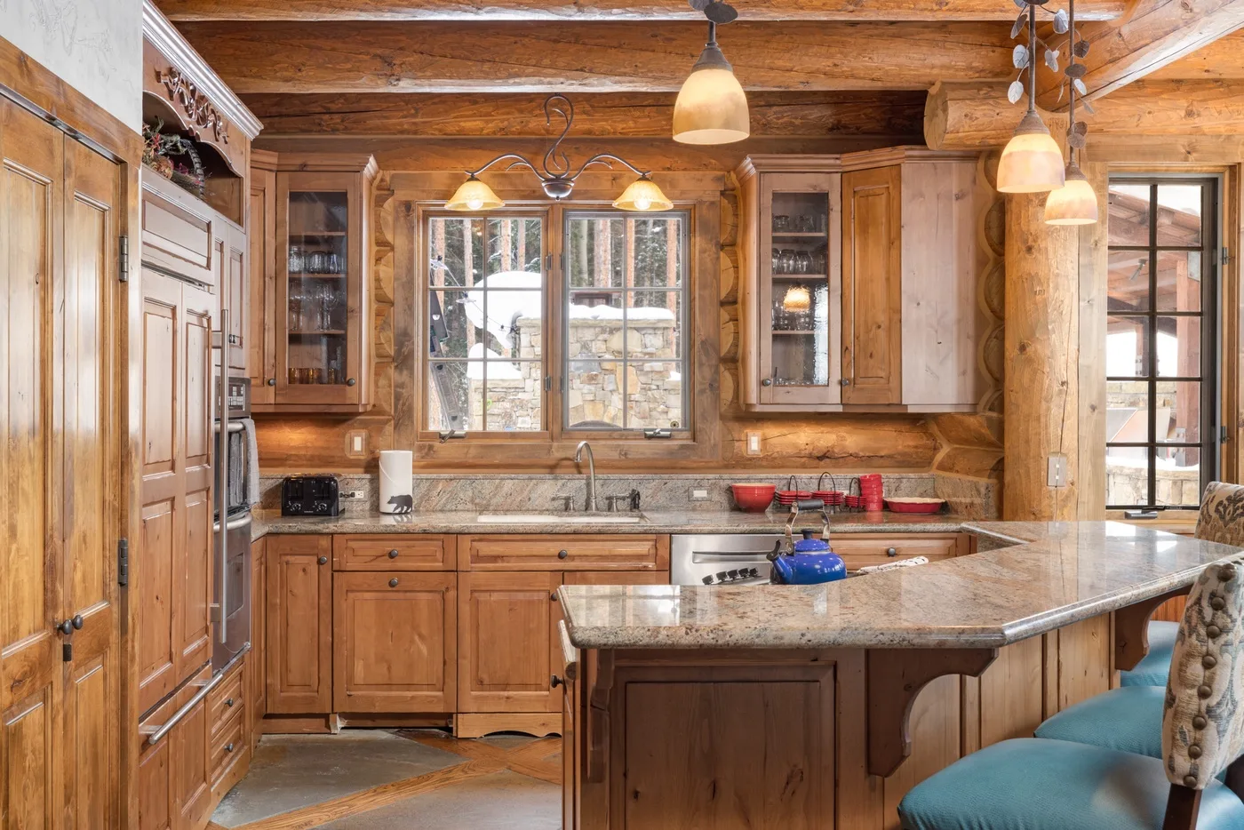 A rustic wood-paneled kitchen with a central island and large windows.