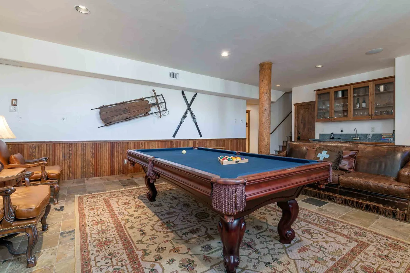 A recreation room with a pool table, seating, and wood-paneled walls.