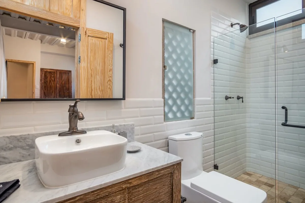 A bathroom with a vessel sink, toilet, and glass shower.