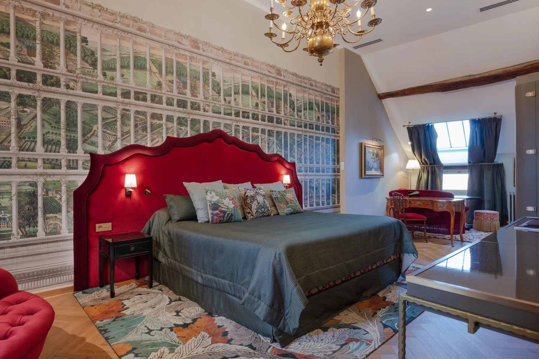 Guest room with a red headboard and a painted panoramic wall scene