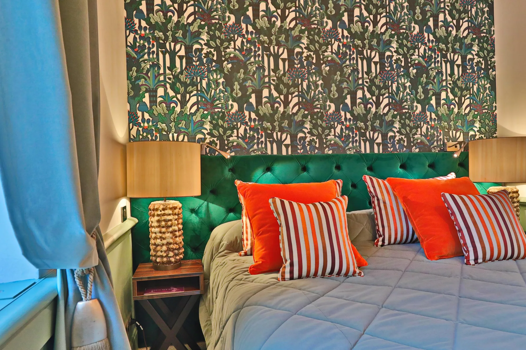 Guest room with a green headboard and colorful floral wall decor