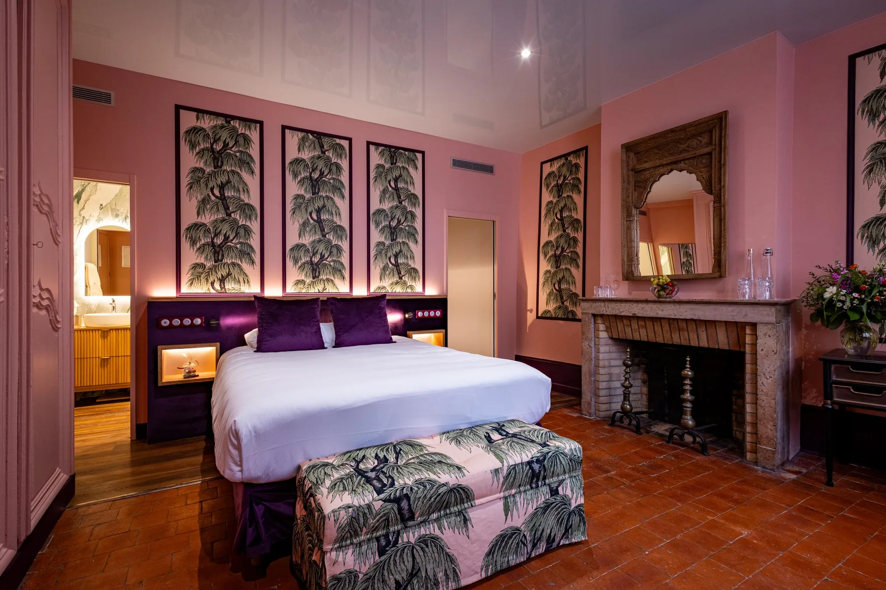 Habitación con cama blanca, chimenea y puerta abierta al baño