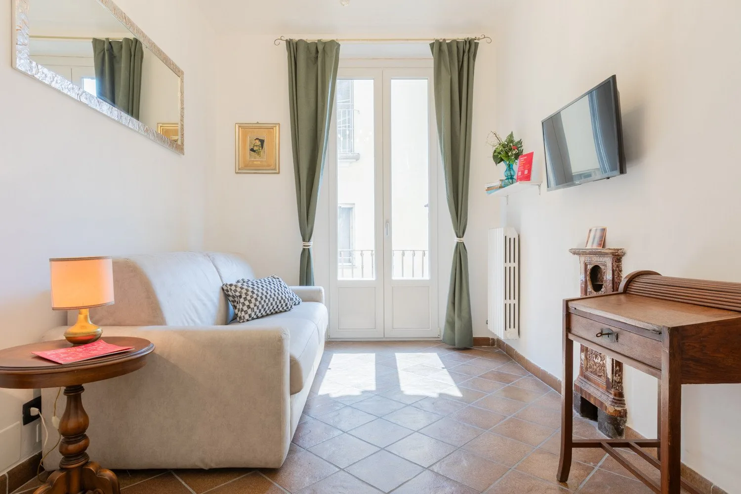 Una sala luminosa con asientos, un televisor y ventanas altas.