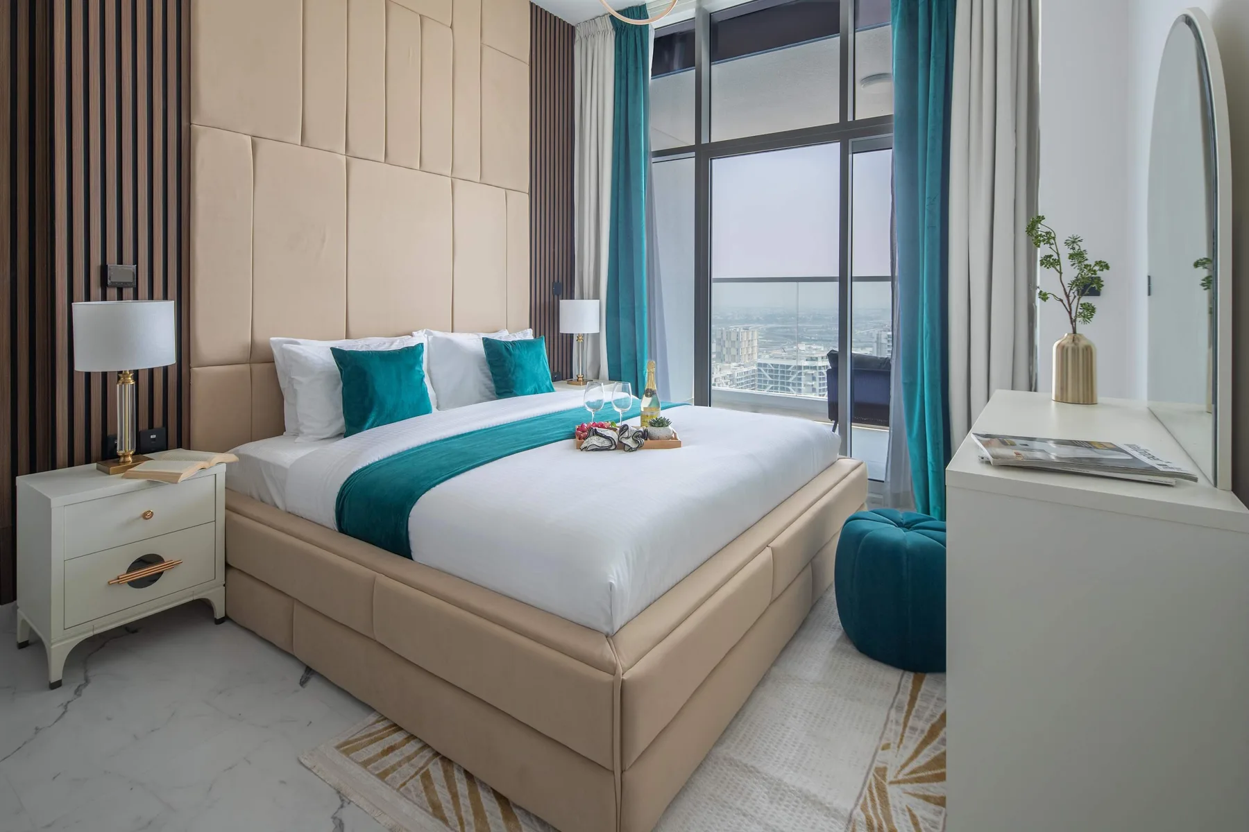 Un dormitorio con una cama bien tendida y grandes ventanas con vistas a la ciudad.