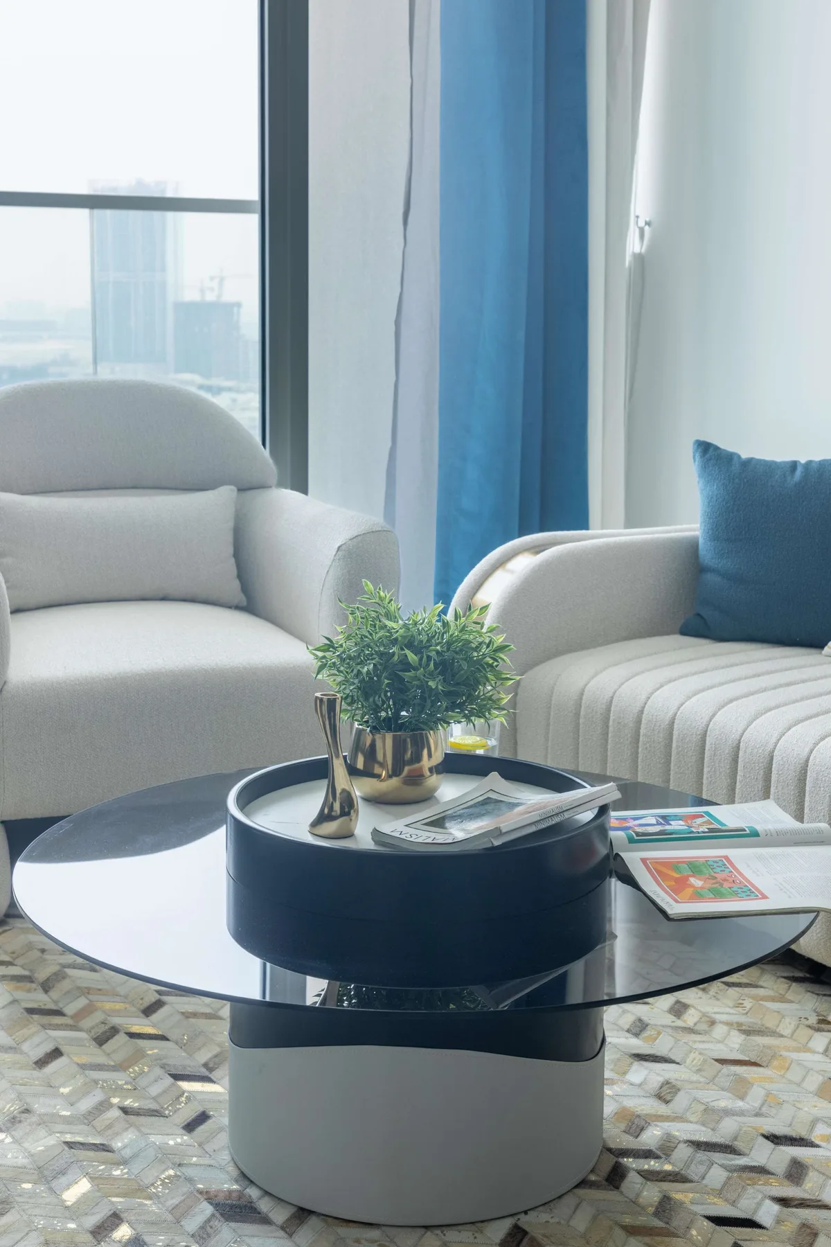 Una sala luminosa con asientos alrededor de una mesa de centro redonda junto a grandes ventanas.