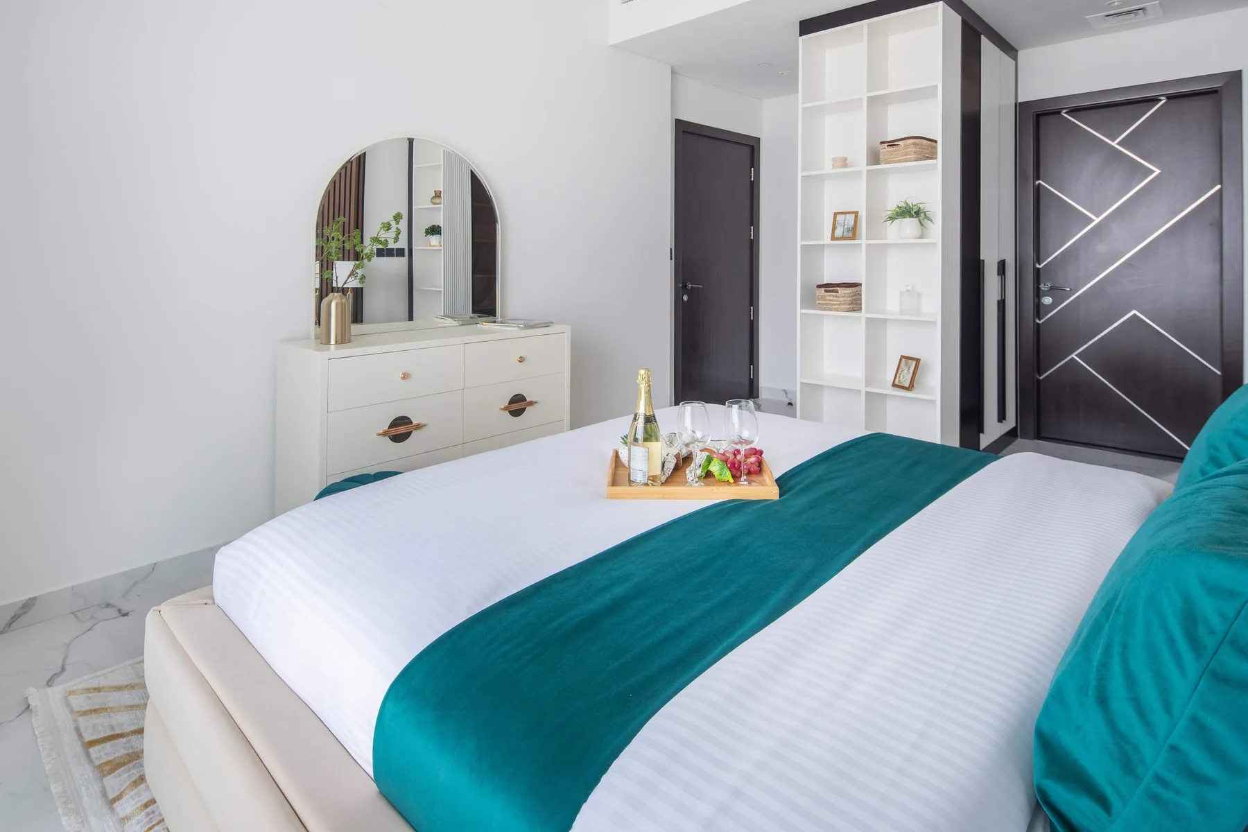 Un dormitorio luminoso con una cama bien hecha y una cómoda blanca.