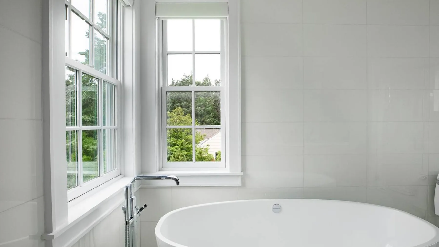 Un baño luminoso con una bañera blanca junto a grandes ventanas.