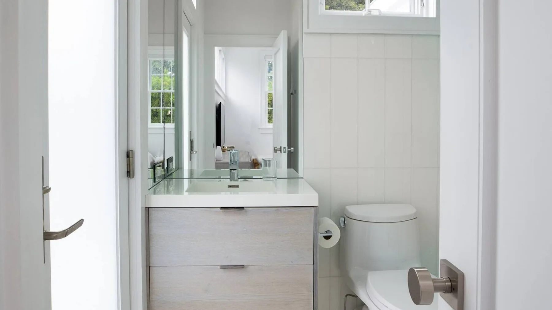Un baño luminoso con lavabo, espejo e inodoro.