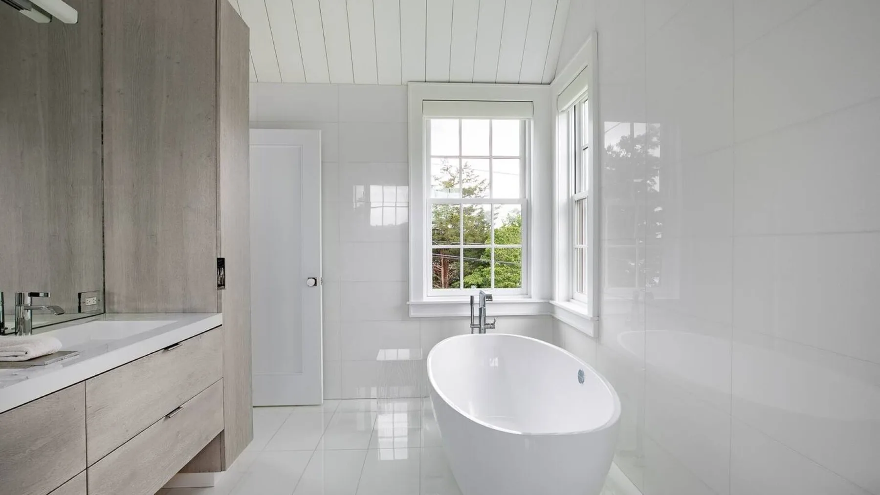 Un baño luminoso con una bañera exenta bajo una ventana.