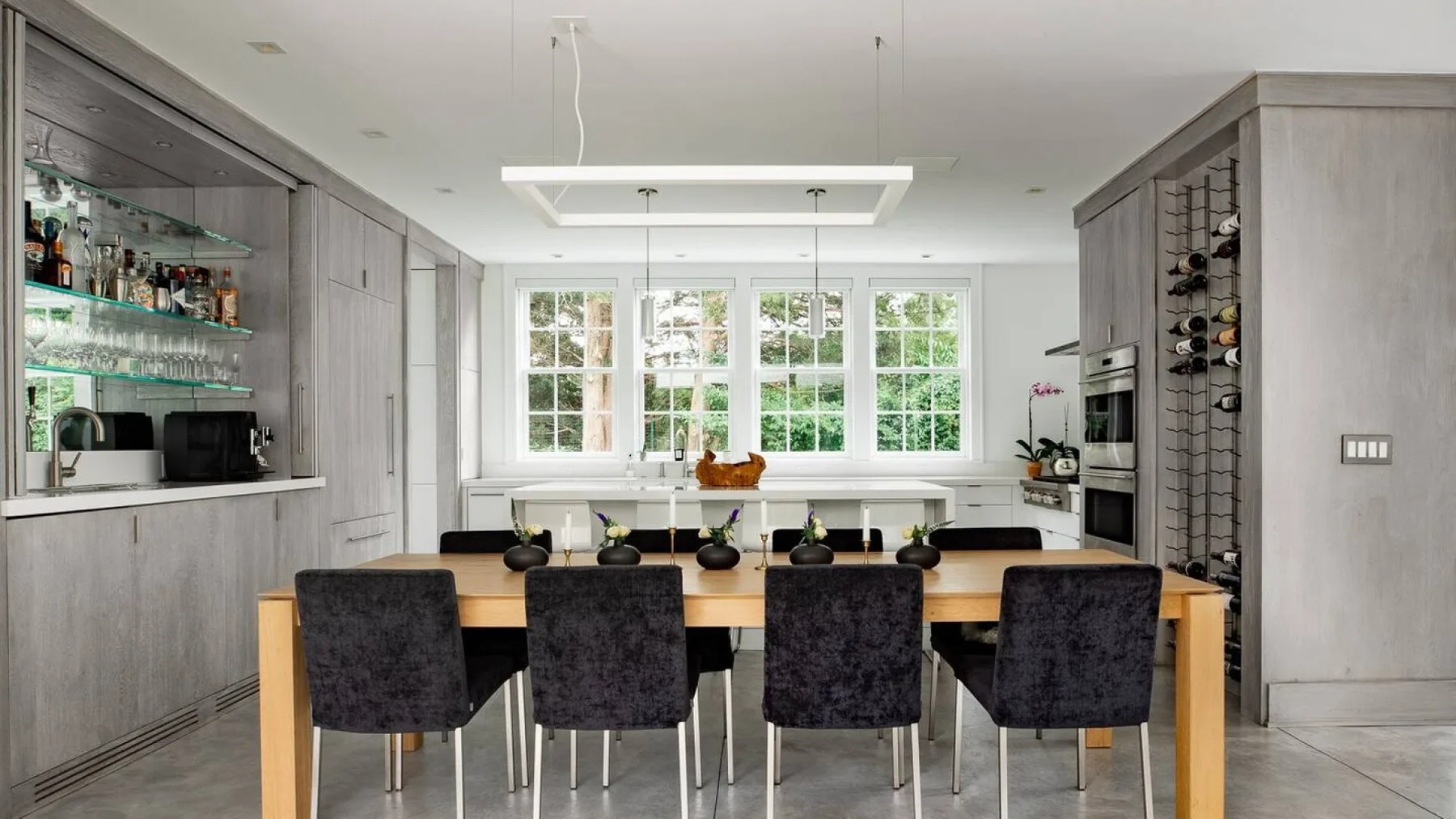 Una cocina luminosa con comedor, una mesa larga y ventanas amplias.