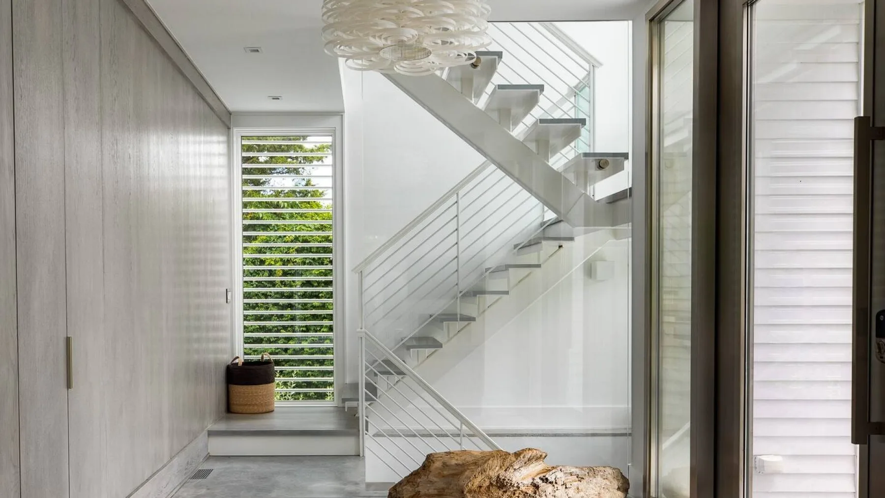 Un interior moderno y luminoso con una escalera y grandes ventanas.
