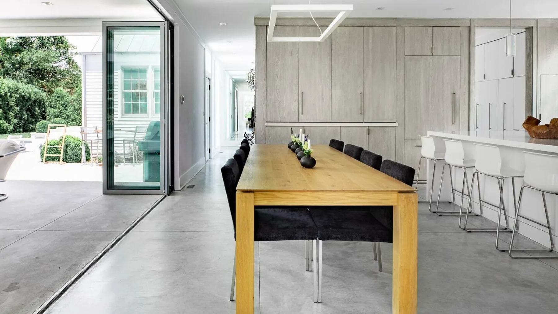 Comedor moderno con una larga mesa de madera junto a una barra de cocina.