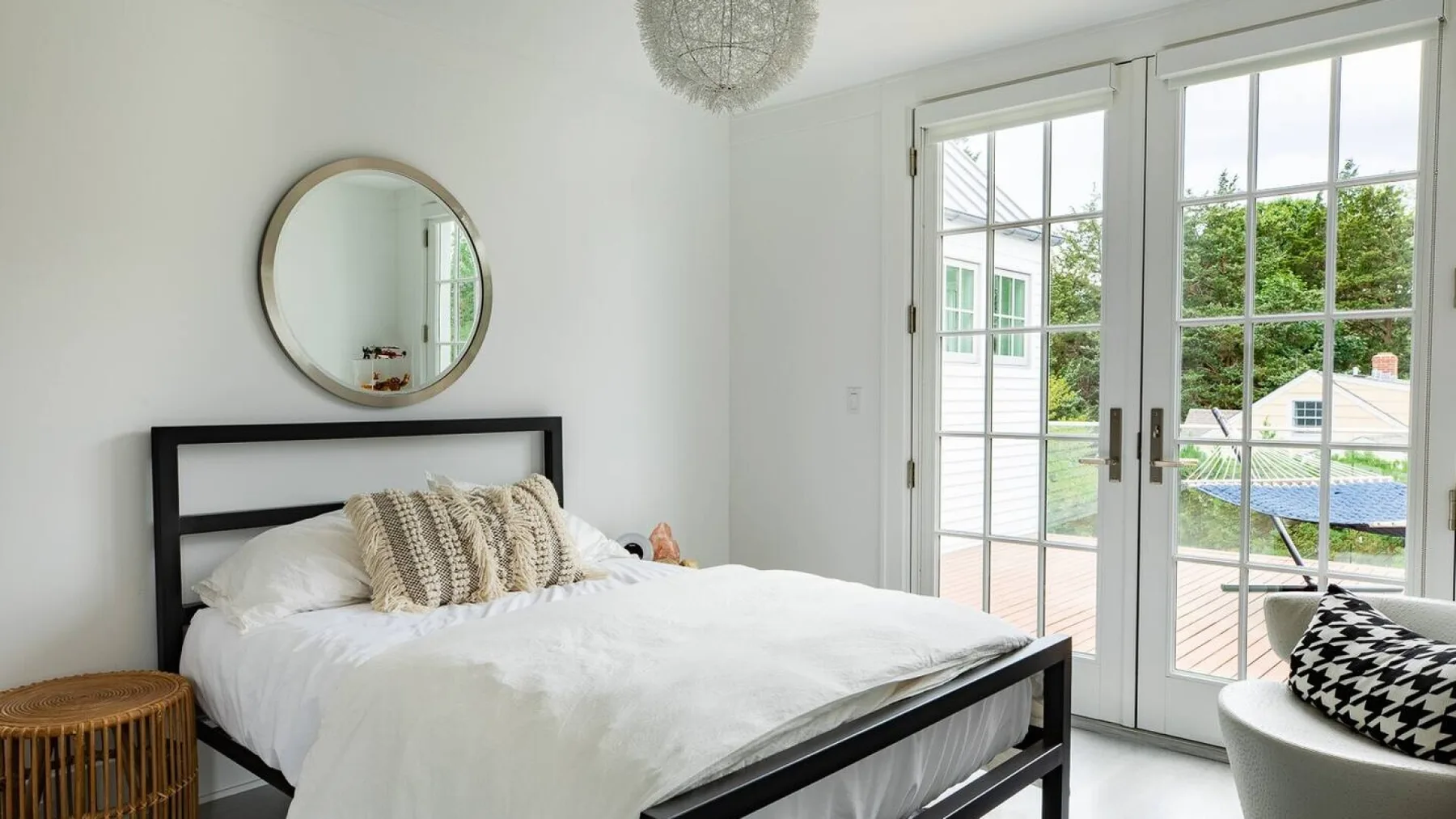 Un dormitorio luminoso con una cama junto a puertas de vidrio que dan a un patio.
