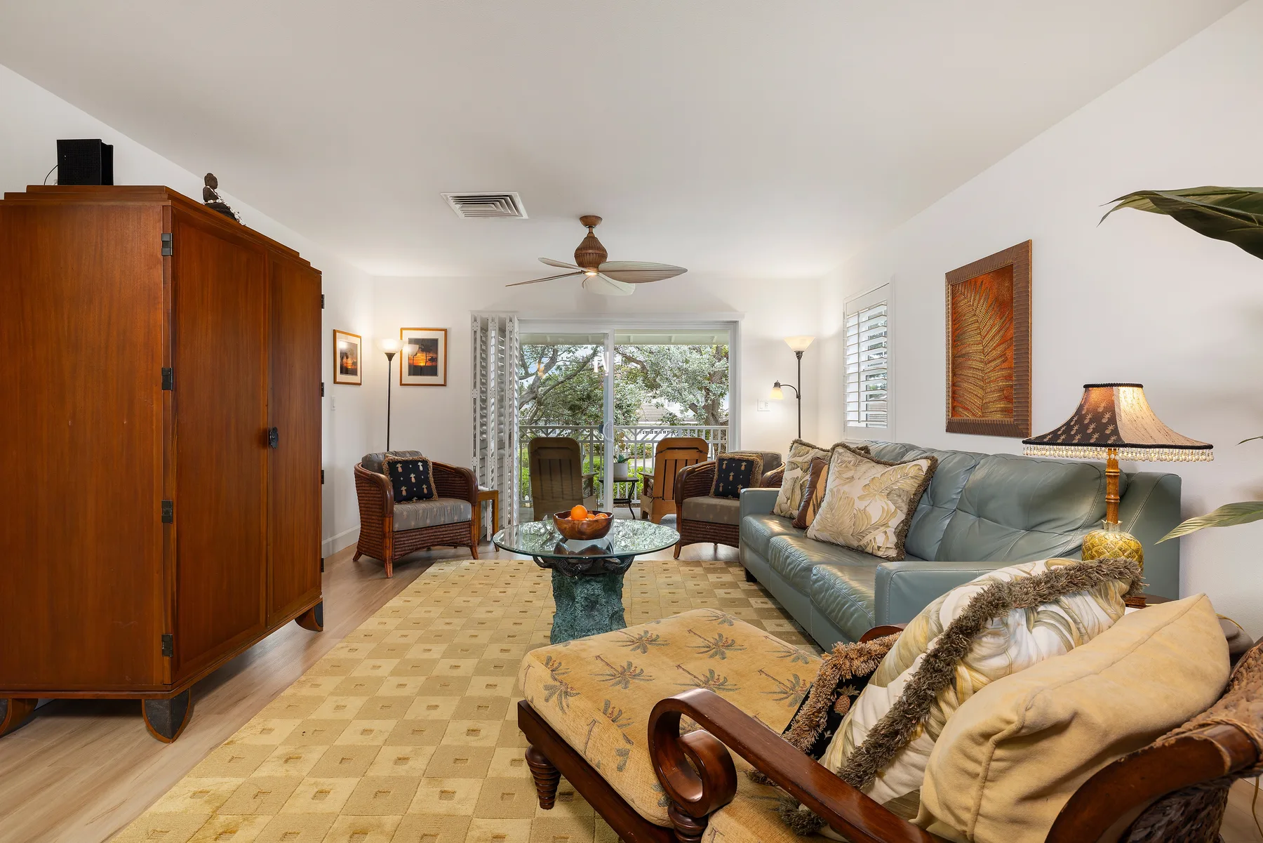 A living room with seating, a glass coffee table, and sliding doors to a patio.