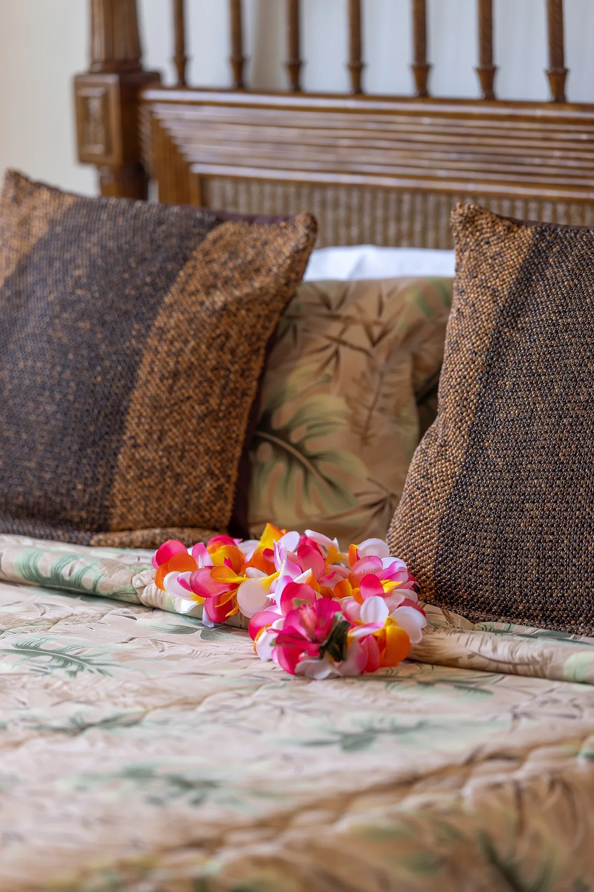 A bed with patterned bedding, textured pillows, and a colorful flower garland.