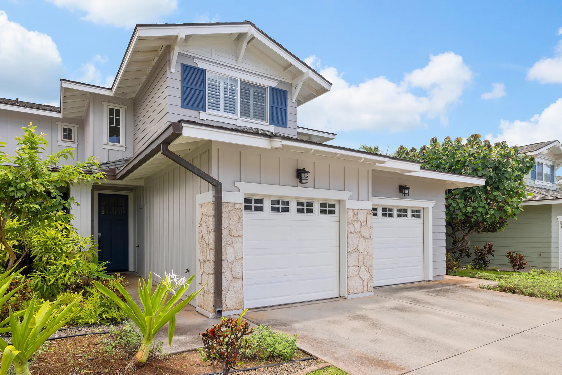 A light-colored house exterior with two garage doors and a driveway.