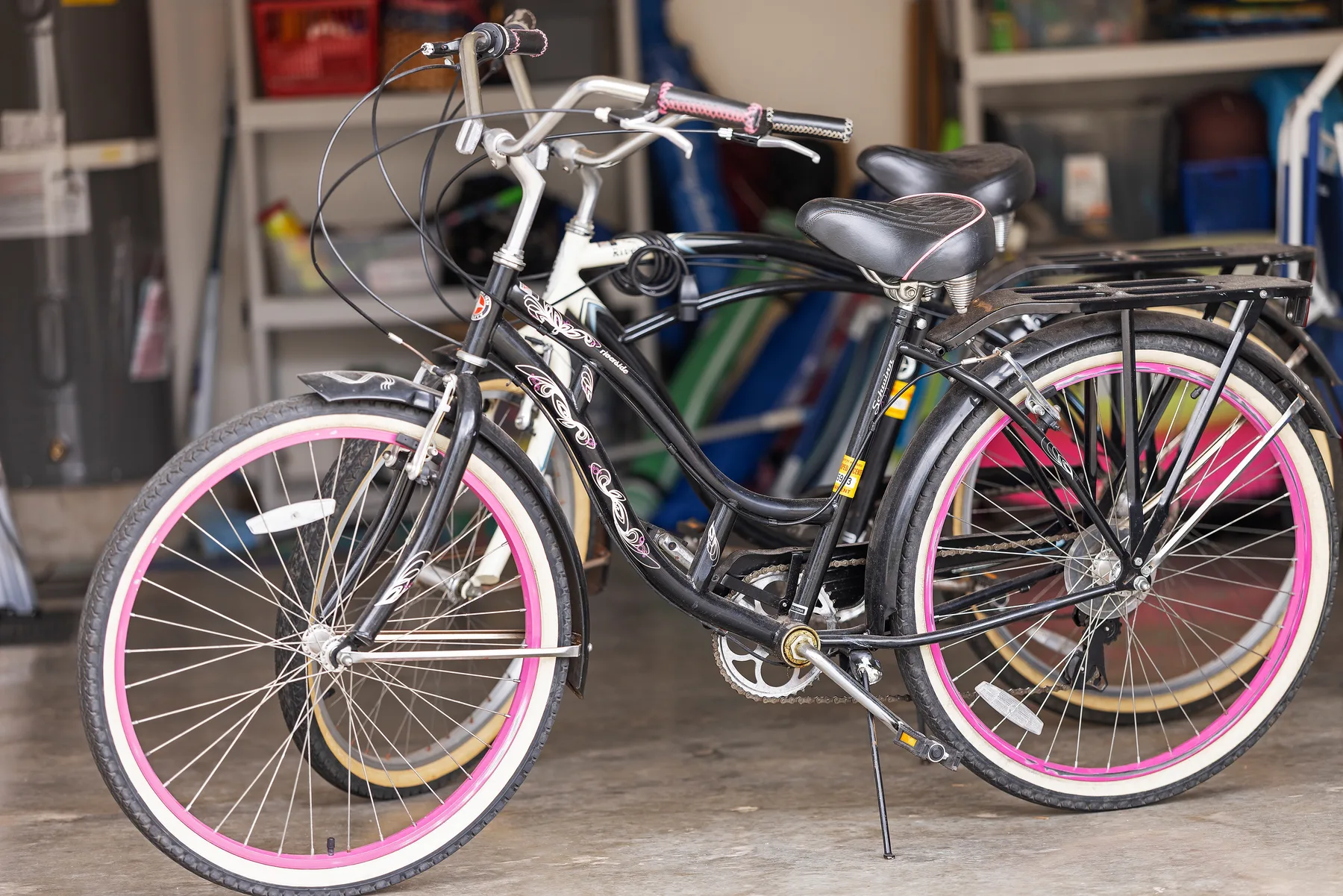 Several bicycles are parked in a garage, with a black bicycle in the foreground.