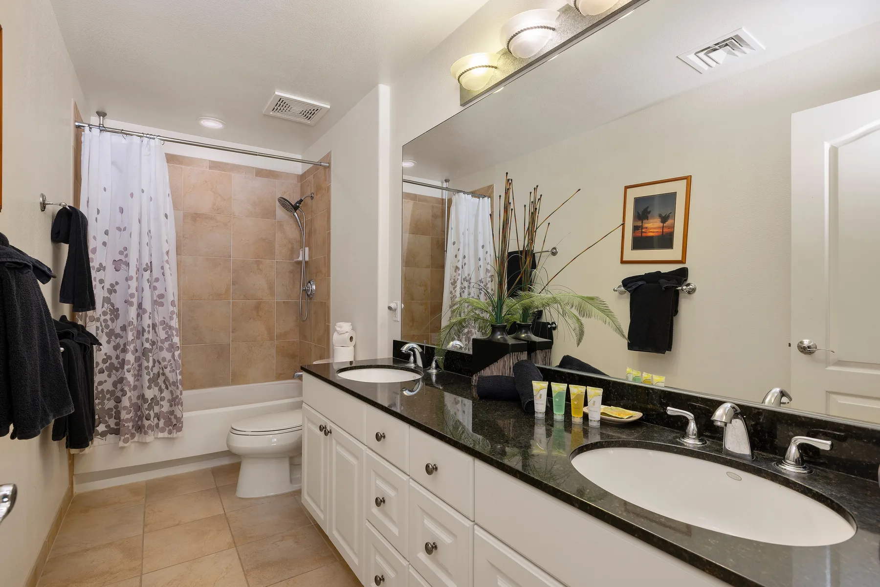 A bathroom with a long vanity, mirror, and bathtub with a shower curtain.