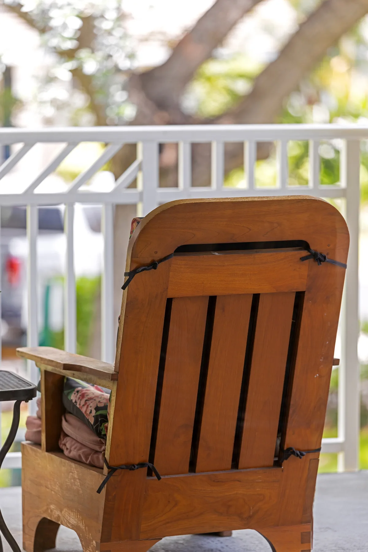 An outdoor seating area with a wooden chair beside a white railing.